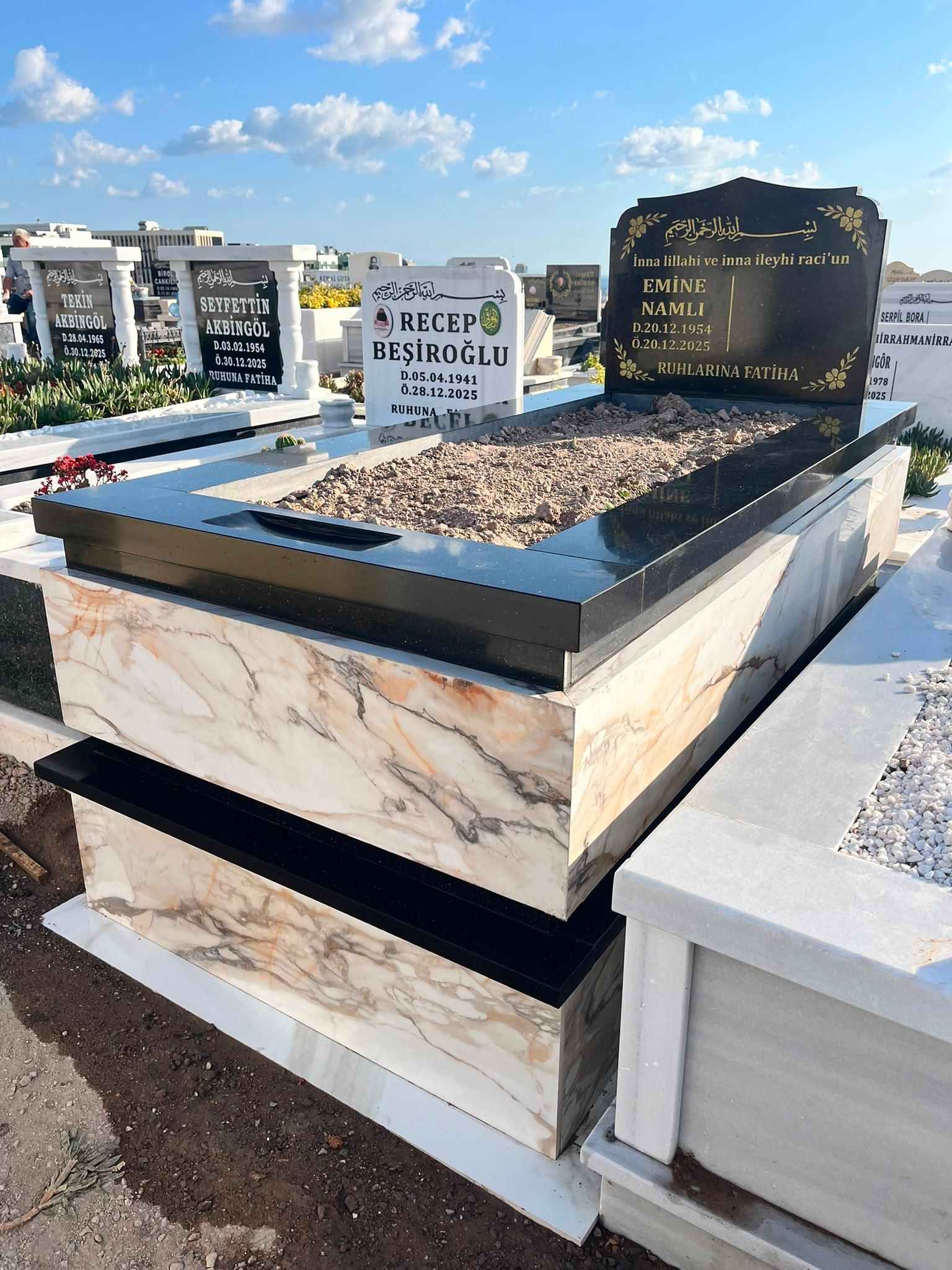 Açık damarlı mermer kaplama ve siyah granit baştaşından oluşan mezar