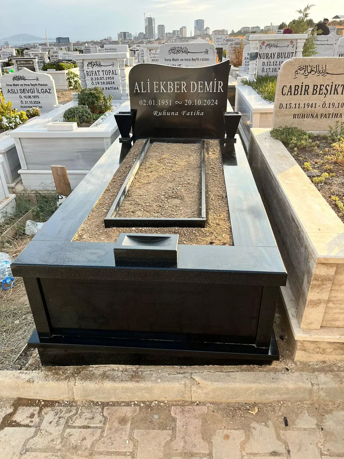 Siyah granit baştaşı ve çerçeveyle tamamlanmış mezar